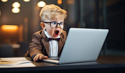 Is your school website working for you? Young child in a blazer, bow tie and glasses using a laptop