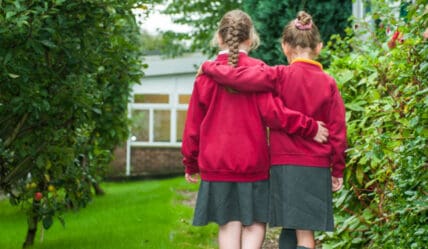 Blog post - building a better school image library. Photo of two school children walking with arms around eachother.
